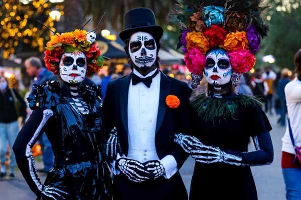 3 people dressed to the nines in dia de los muertos costumes