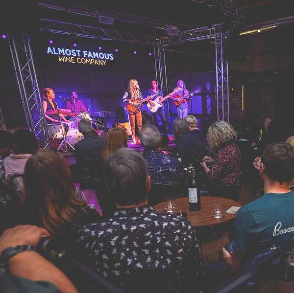 a band on stage and a room full of people watching them with wine