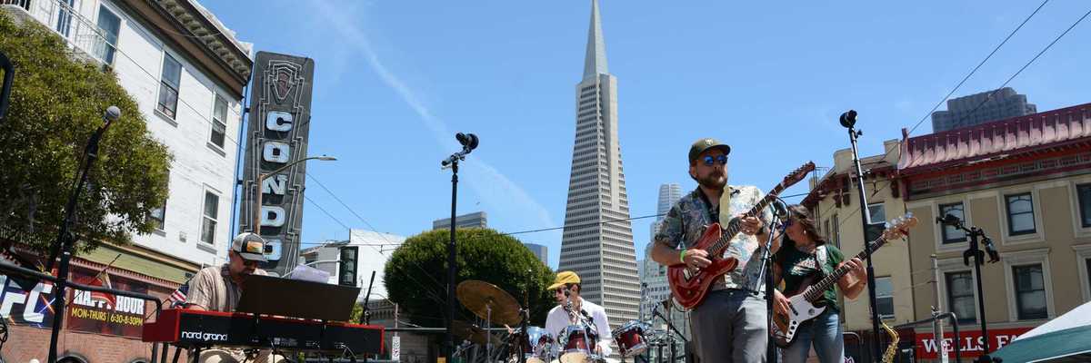 A band playing on a stage with the Transamerica Pyramid behind them