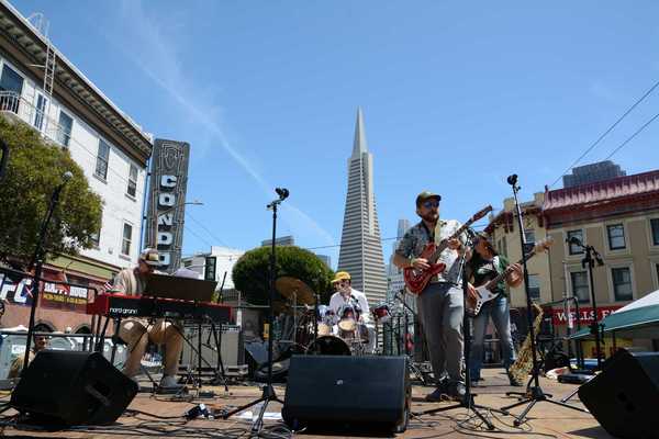 A band playing on a stage with the Transamerica Pyramid behind them