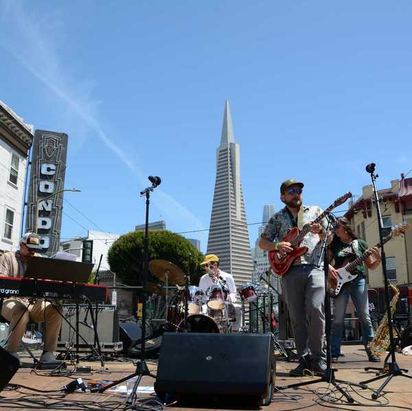 A band playing on a stage with the Transamerica Pyramid behind them