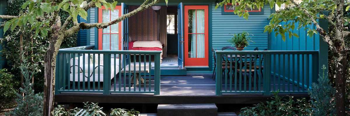 A blue cottage with red doors and funky wallpaper inside