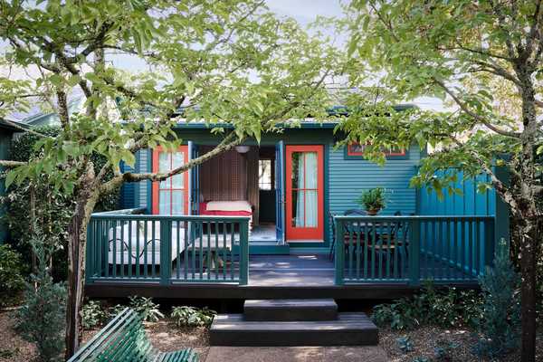 A blue cottage with red doors and funky wallpaper inside
