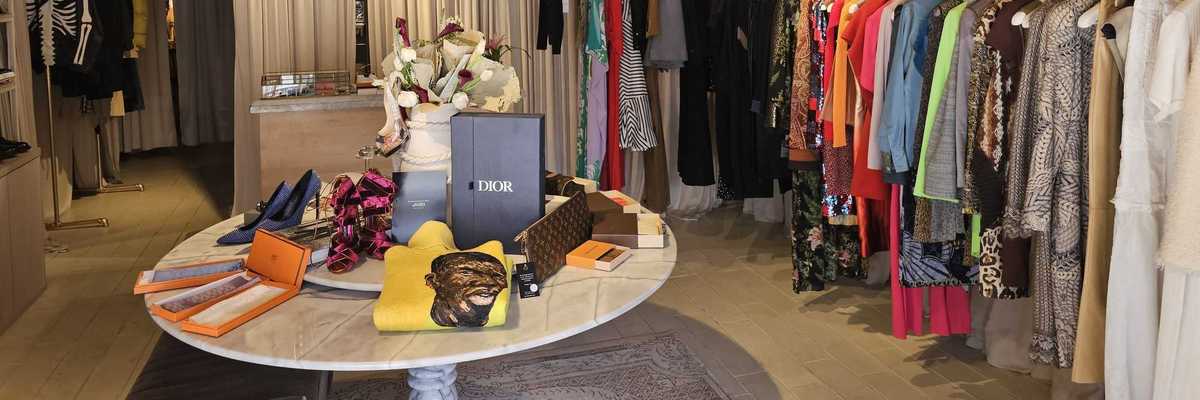 a boutique shop with clothes racks around the edges and a table with accessories in the middle