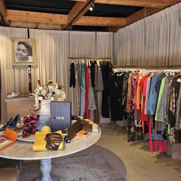 a boutique shop with clothes racks around the edges and a table with accessories in the middle