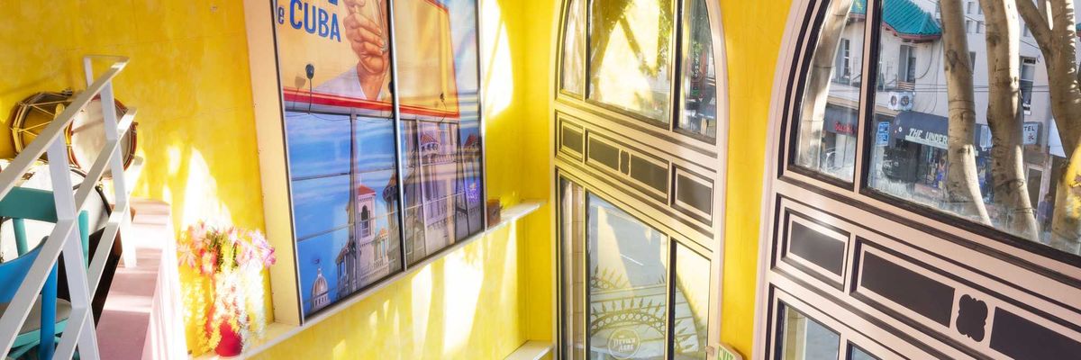 a brightly colored, two story bar with large windows onto the street