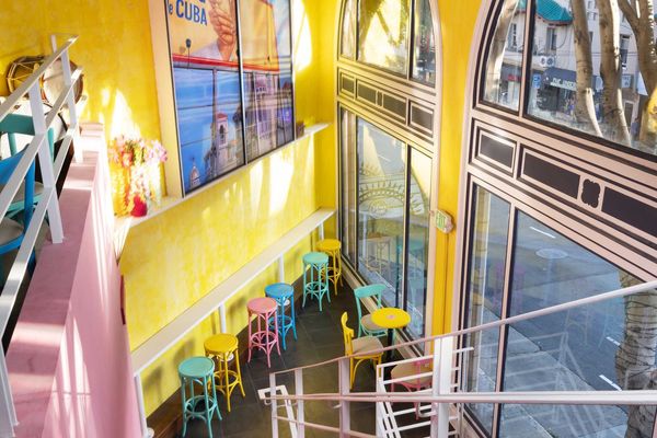 a brightly colored, two story bar with large windows onto the street