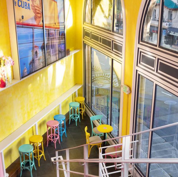 a brightly colored, two story bar with large windows onto the street