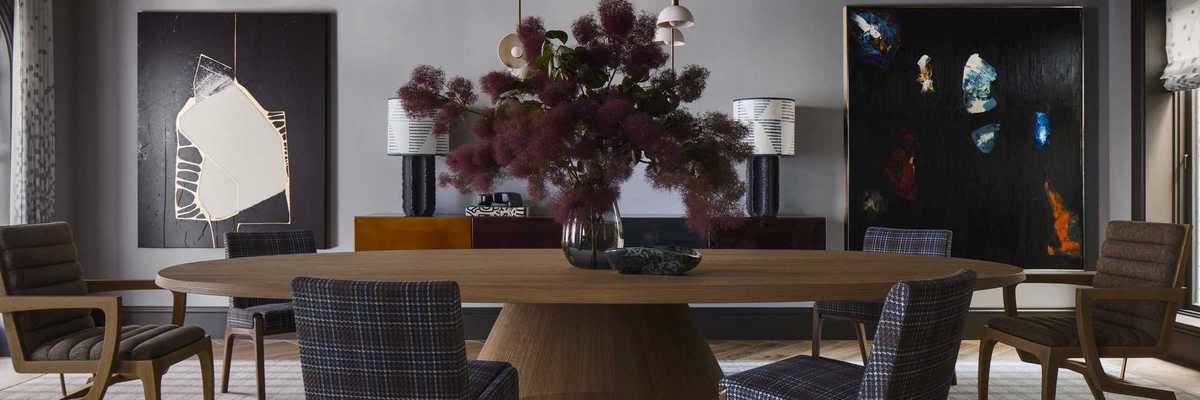 a chic dining room with plaid chairs, a big flower arrangement, large format art, and a sculptural light