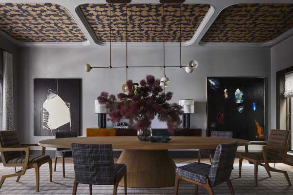 a chic dining room with plaid chairs, a big flower arrangement, large format art, and a sculptural light