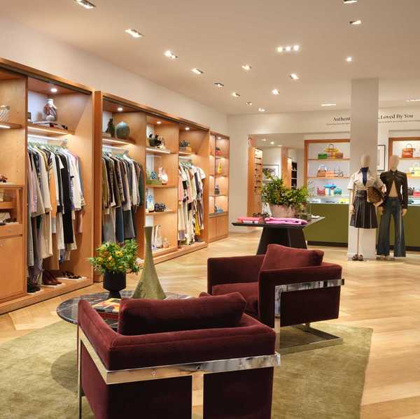 a clothing store with wooden built in closets and burgandy seating