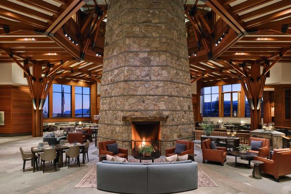 a cozy lounge with a large stone fireplace, wood beams, and lots of seating