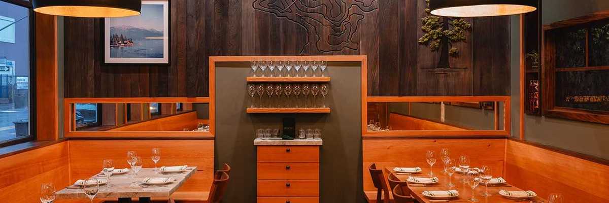 a cozy restaurant with wood paneling and tables against the walls