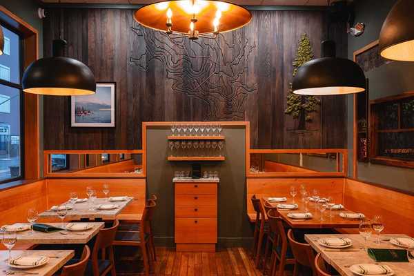 a cozy restaurant with wood paneling and tables against the walls