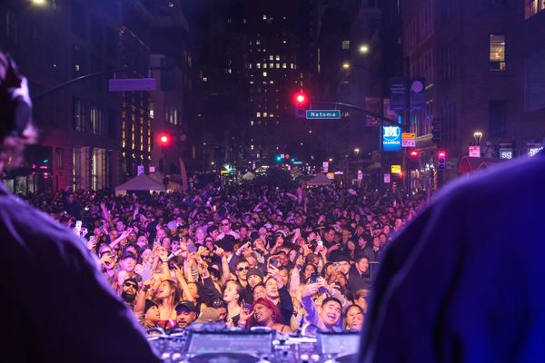 a crowd of people dancing in front of a dj booth outdoors