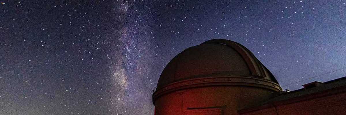 a detailed starry sky next to an observatory at night