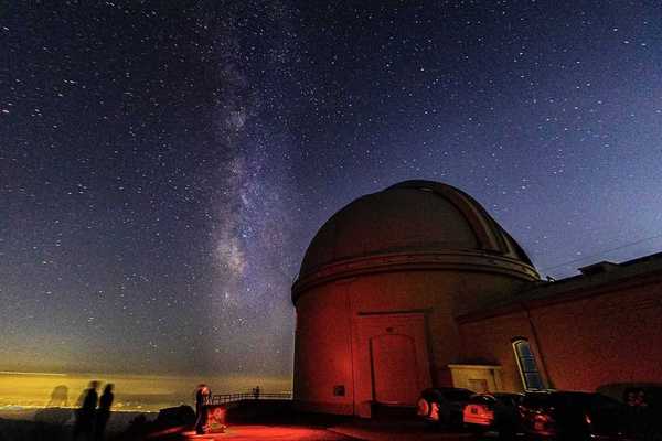 a detailed starry sky next to an observatory at night