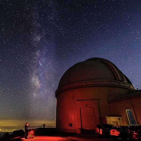 a detailed starry sky next to an observatory at night
