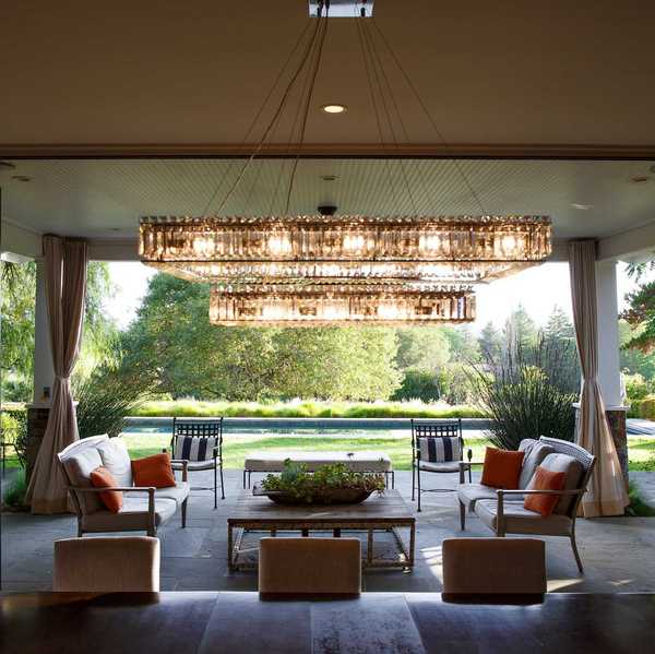 a dining room opening onto a patio with a large chandelier and a pool in the background