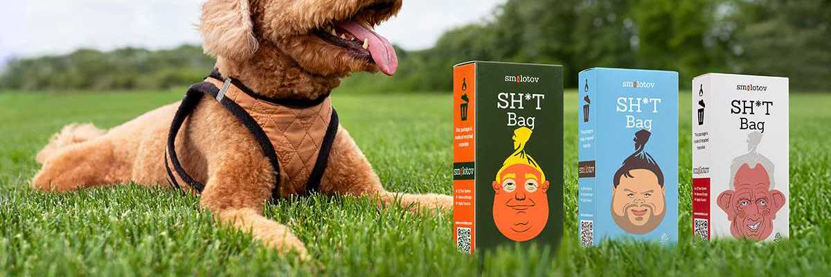 a dog laying on the grass with three boxes of Smolotov shit bags in front of him