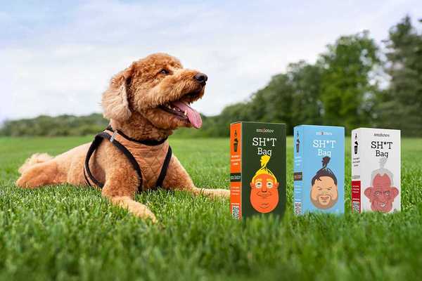 a dog laying on the grass with three boxes of Smolotov shit bags in front of him