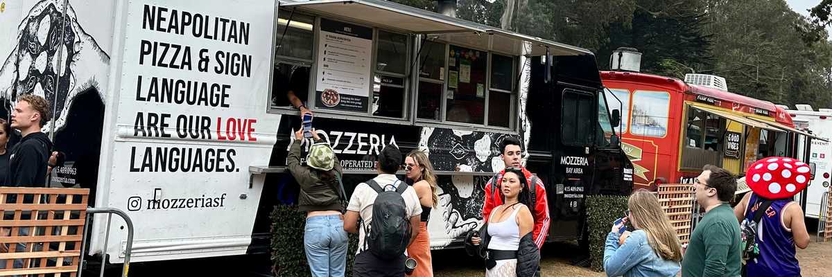 a food truck with a sign for neapolitan pizza and sign language with a line of people waiting to order