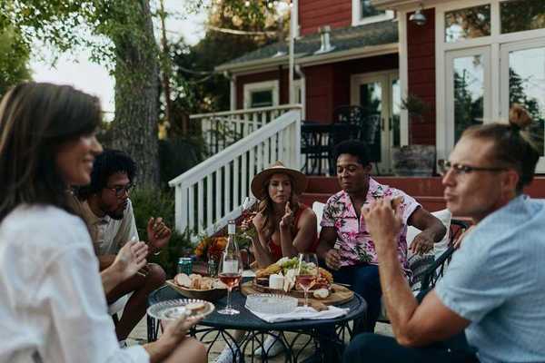 a group of people sitting around a table set with cheese and wine