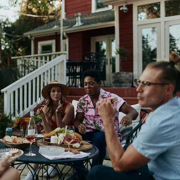 a group of people sitting around a table set with cheese and wine