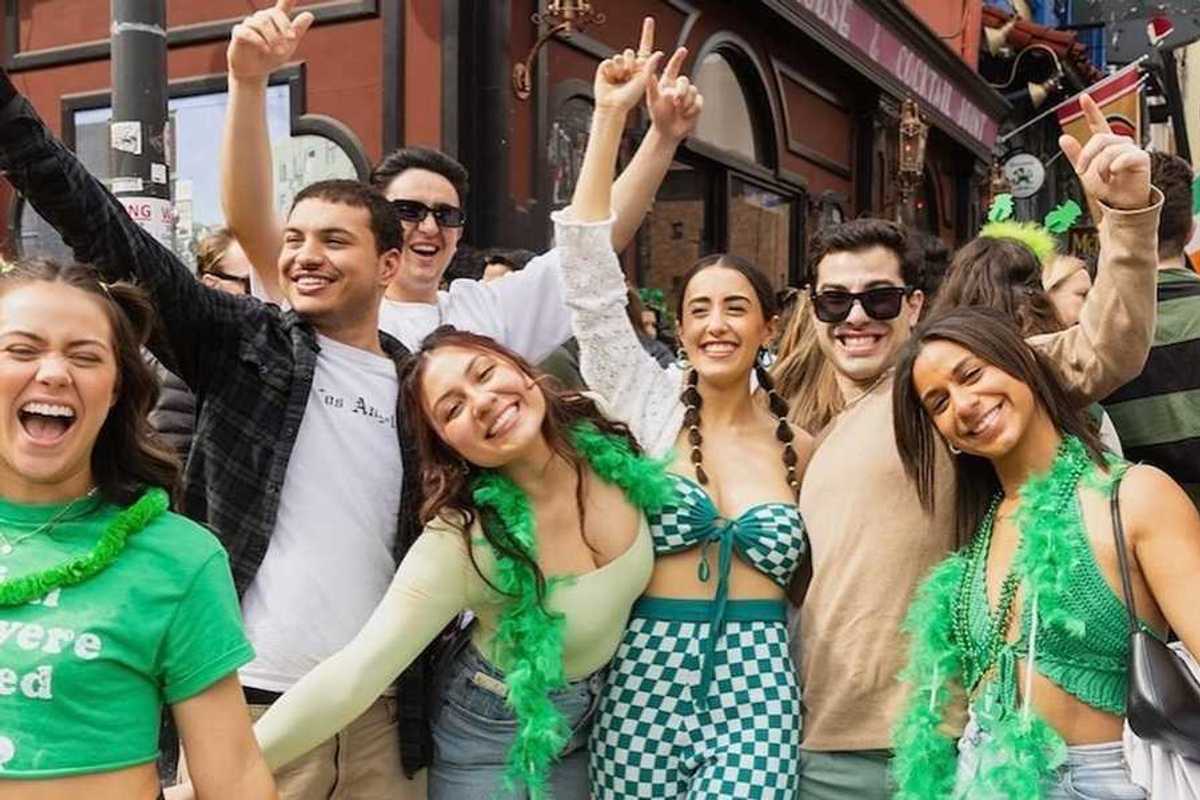 a group of young people wearing green and posing in front of an Irish pub