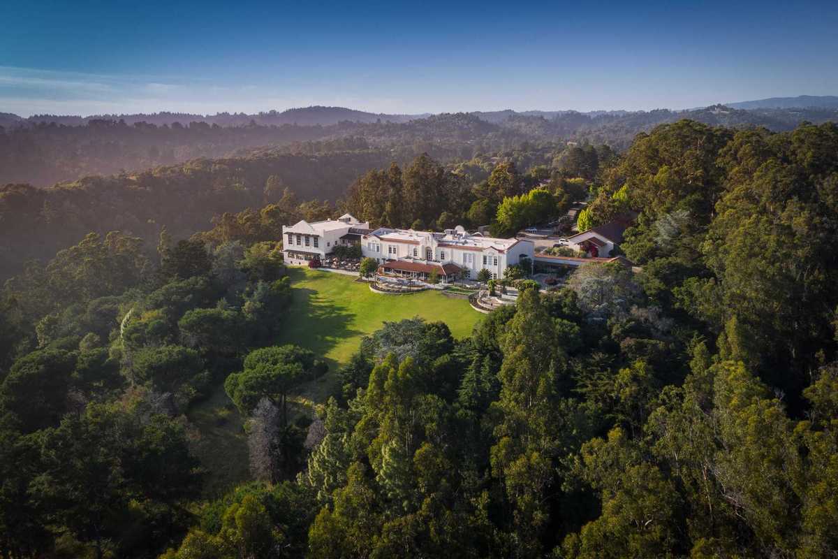 a hacienda-like hotel on a hill surrounded by forest