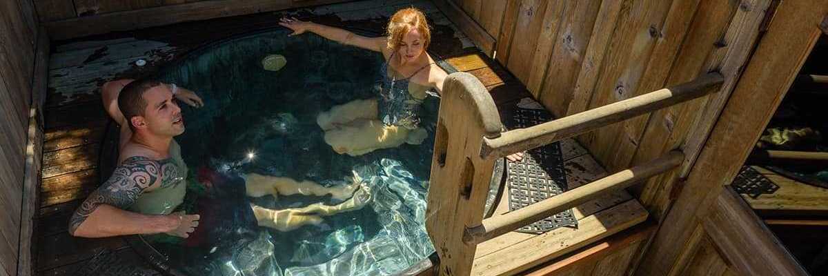 A heterosexual couple in a tub in a wooden cabin