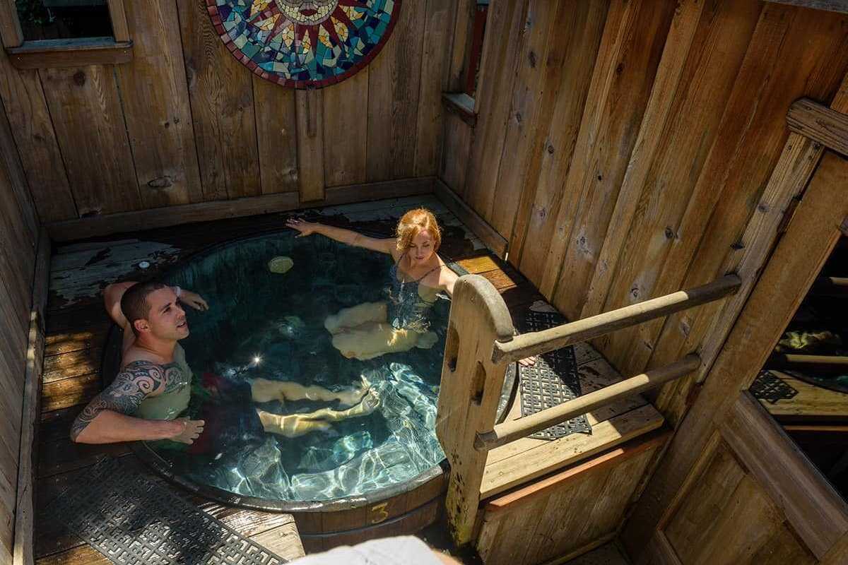 A heterosexual couple in a tub in a wooden cabin