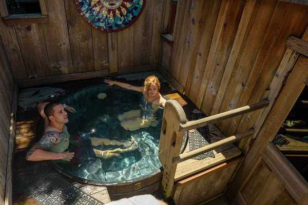 A heterosexual couple in a tub in a wooden cabin