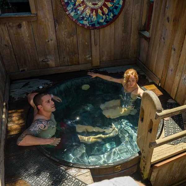 A heterosexual couple in a tub in a wooden cabin