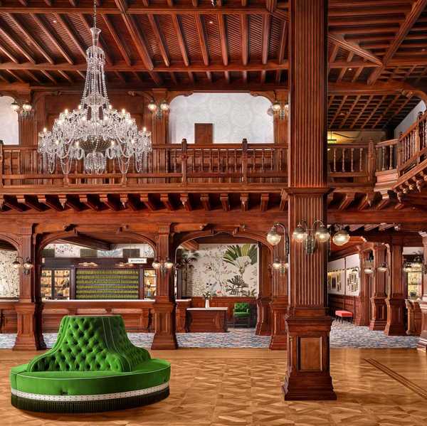 a hotel loby with elaborate wood ceiling and columns and a green lounge area