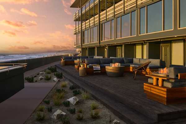 a hotel with a broad patio and seating on the beach in the sunset