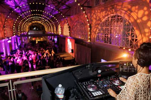 a large hall with purple lights, a dj, and people dancing