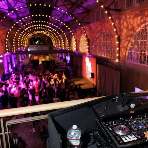 a large hall with purple lights, a dj, and people dancing