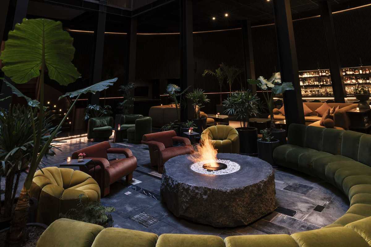 a living room like lounge with a fire pit and a bar in the background