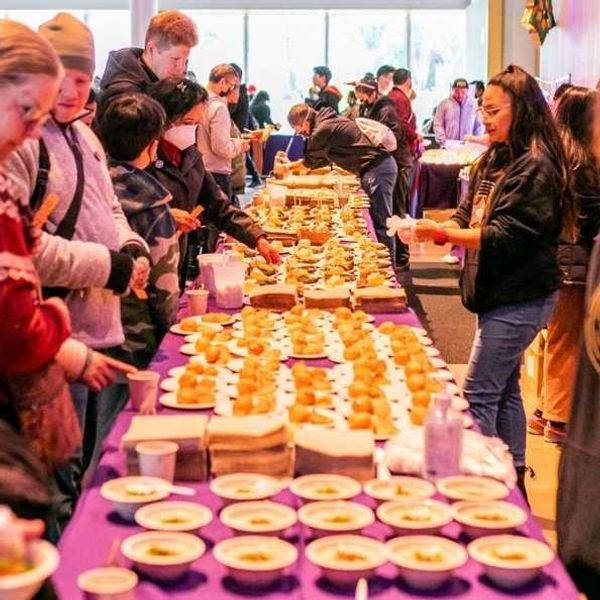 a long table with a purple tablecloth and sweet laid out down the entire length