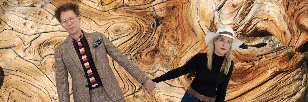 A man and women of holding hands in front of a tree ring patterned background
