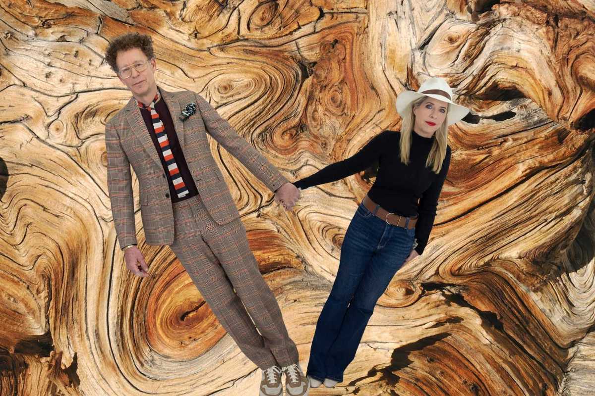 A man and women of holding hands in front of a tree ring patterned background
