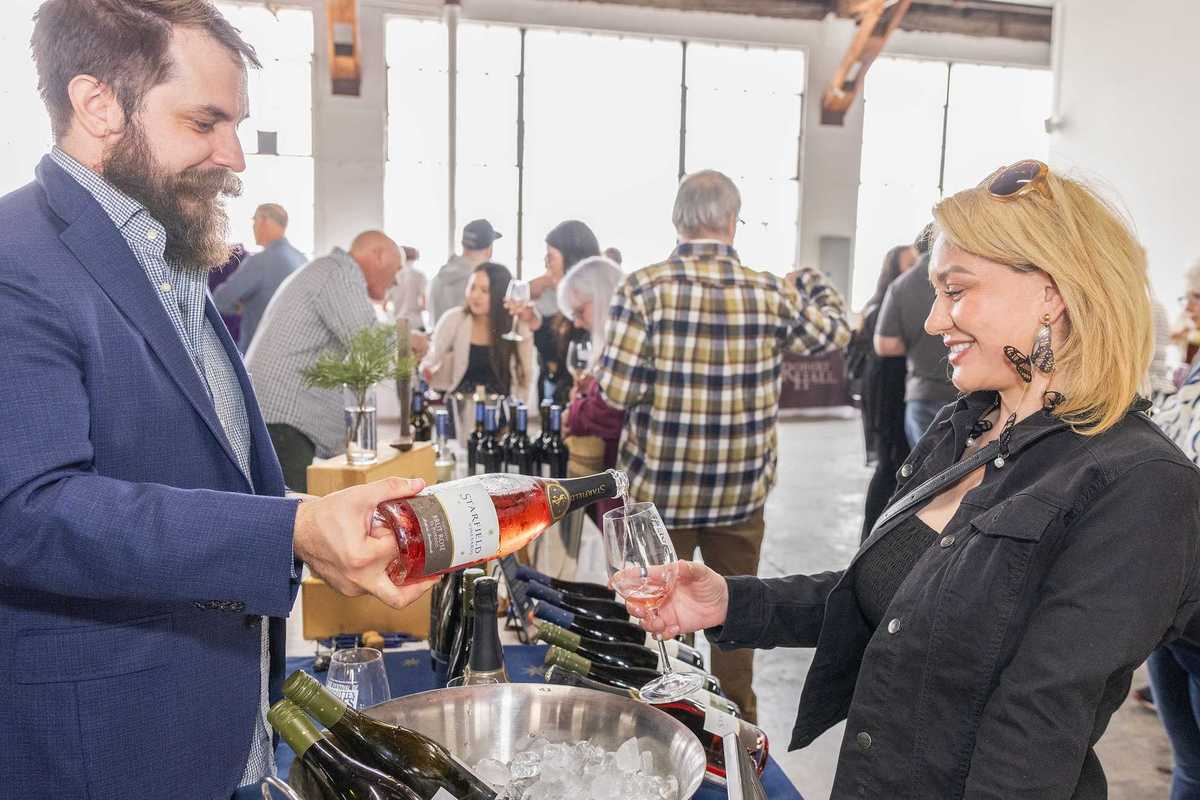 a man pouring wine into a glass for a woman at a wine festival