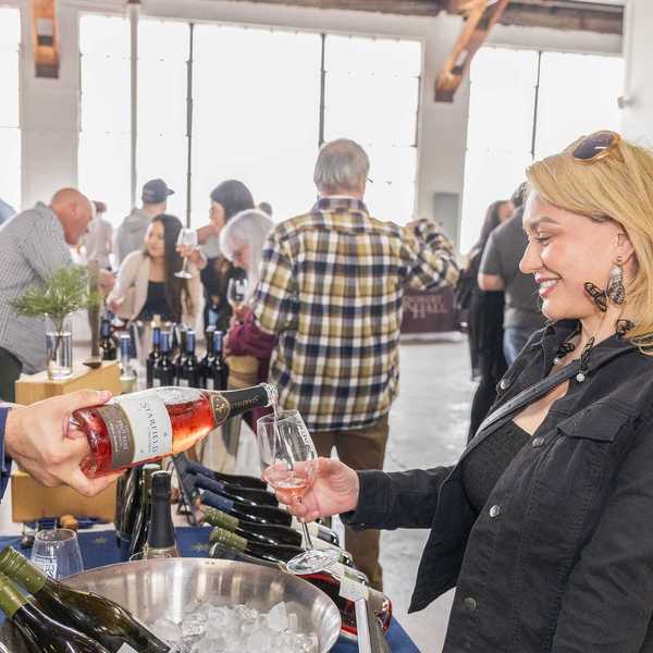 a man pouring wine into a glass for a woman at a wine festival
