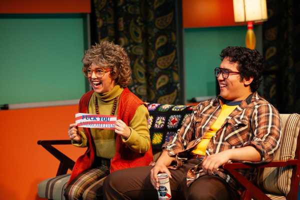 a middle aged woman and man in 1970s clothing laughing at a TV
