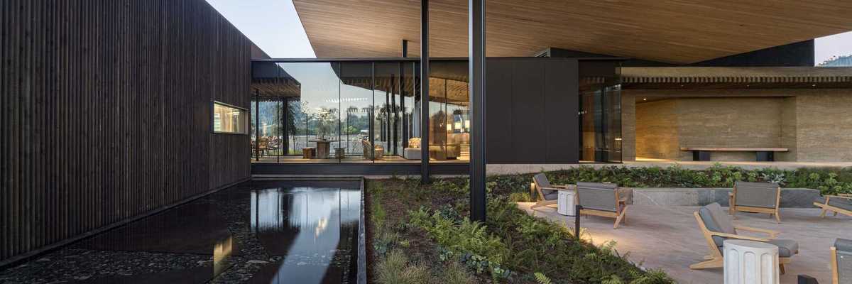 a modern architectural image with a shallow pool and a patio set with chairs