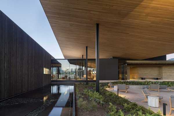 a modern architectural image with a shallow pool and a patio set with chairs