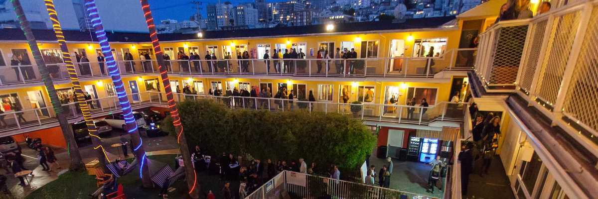 a motel around a pool lit up with art galleries in each room