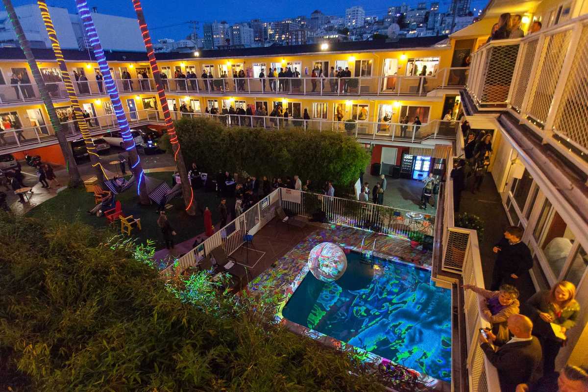 a motel around a pool lit up with art galleries in each room