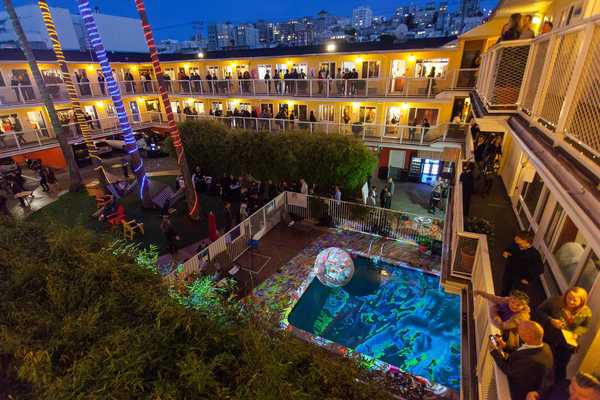 a motel around a pool lit up with art galleries in each room